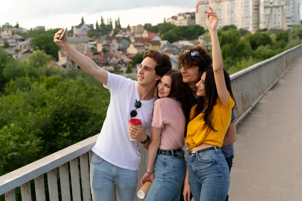 group four friends spending time together outdoors taking selfie
