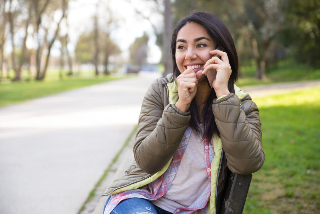 Excited young woman laughing while talking on phone