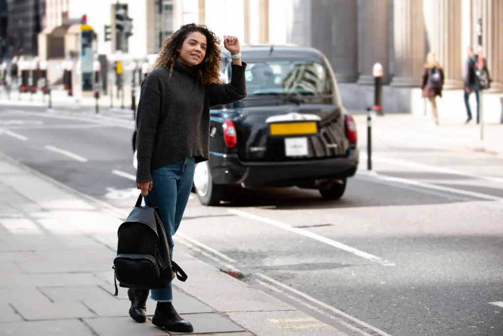 mujer joven preparandose para detener un taxi en la ciudad