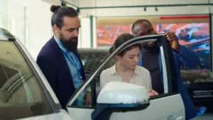 agente de concesionario de automoviles que demuestra los clientes la durabilidad de las puertas del vehiculo