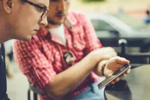 los hombres comparten noticias fotos y videos en el telefono inteligente un hombre muestra un amigo una aplicacion en un telefono movil amigos con un telefono inteligente la tecnologia