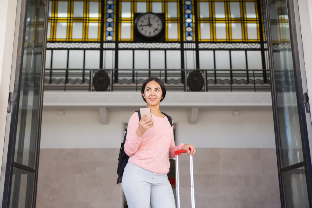 smiling woman standing with suitcase station hall