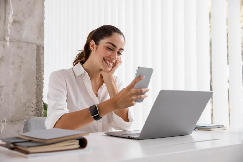 vista lateral de la empresaria sonriente con smartphone y portatil