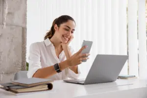 vista lateral de la empresaria sonriente con smartphone y portatil