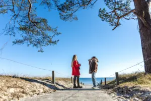 dos mujeres bebiendo cafe caliente de un termo en el muelle natural de la costa