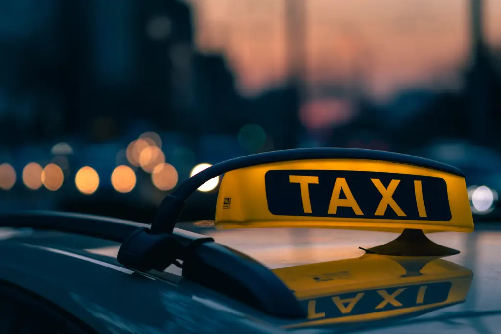 primer tiro de un cartel de taxi en los colores calidos del atardecer con luces bokeh de fondo