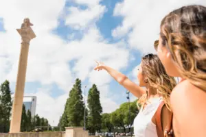 woman looking her female friend pointing finger pillar park
