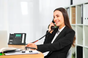 empresaria joven que sonrie mientras que habla en el telefono en la oficina