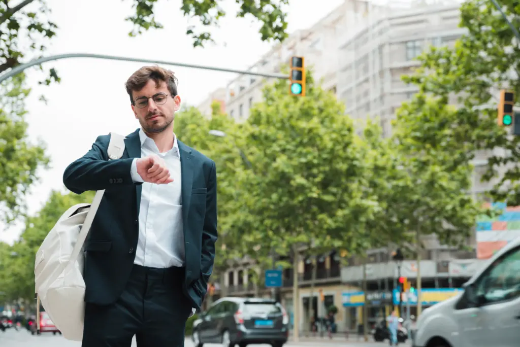 retrato de un joven empresario de pie en la calle de la ciudad comprobando el tiempo