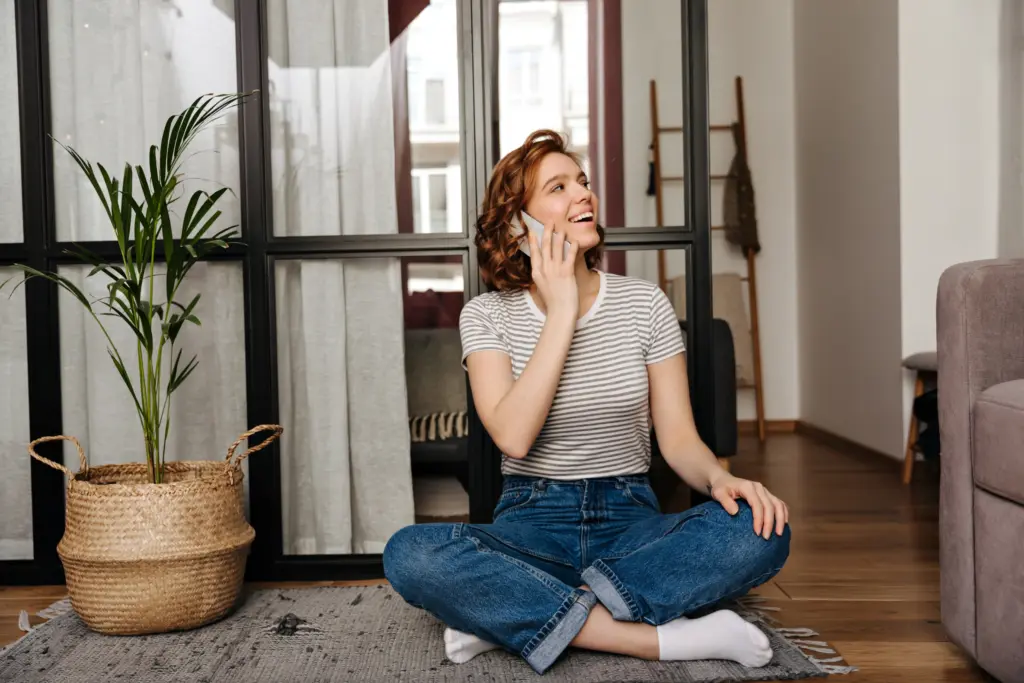 lovely woman jeans is sitting floor living room talking phone